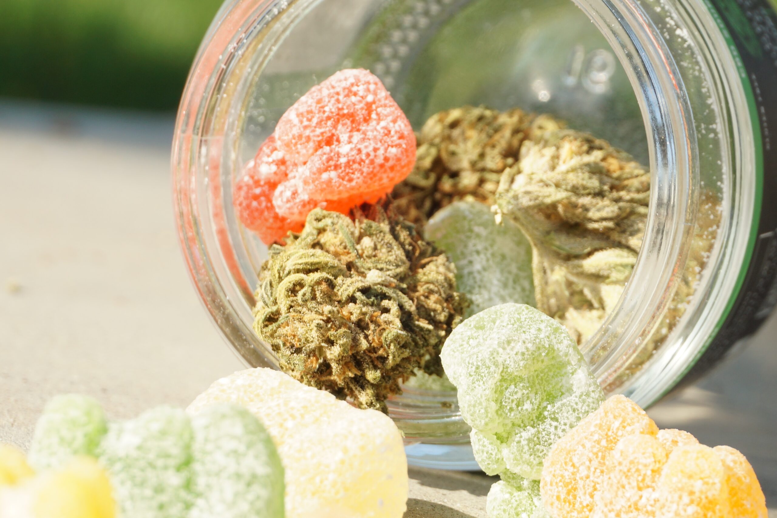 photo of cannabis flower and green and yellow cannabis edible gummies in clear mason jar